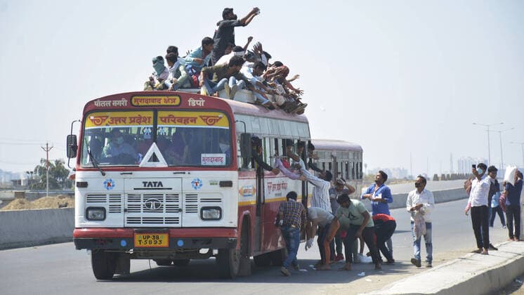 GHAZIABAD, INDIA - MARCH 28: People distribute food to migrant workers as they head to their native state on a bus during Day 4 of the 21 day nationwide lockdown -- to check the spread of coronavirus, at Lal Kuan bus stand, on March 28, 2020 in Ghaziabad, India. (Photo by Sakib Ali Hindustan Times ) Coronavirus Update: Amid Lockdown, A Sea Of Migrants In Delhi-NCR Try To Find Their Way Back Home