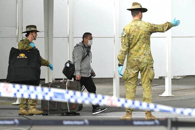 AUSTRALIA CORONAVIRUS COVID-19, A member of the Defence Force watches over as returning overseas travellers are ushered towards waiting busses for the beginning of their 14-day imposed quarantine after arriving at Sydney International Airport in Sydney, Sunday, March 29, 2020. ( NO ARCHIVING, EDITORIAL USE ONLY, NO USE IN BOOKS WITHOUT CONSENT SYDNEY NSW AUSTRALIA  Copyright: xJOELxCARRETTx 20200329001460668353