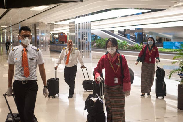 28.03.2020, Singapur, Republik Singapur, Asien - Piloten und Flugbegleiter der Druk Air aus Bhutan tragen bei ihrer Ankunft im Terminal 1 am Flughafen Changi Atemschutzmasken und Gummihandschuhe, um sich vor einer Ansteckung mit dem pandemischen Coronavirus zu schuetzen.