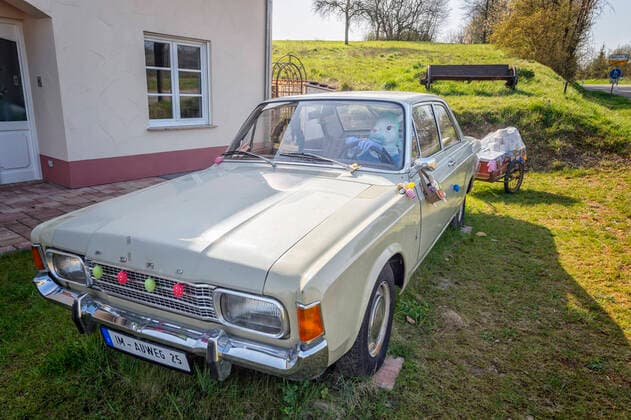 28.03.2020, Saarland, Mandelbachtal. Ein Osterhase sitzt am Samstag in Bliesmengen Bolchen in einem Ford Taunus im Vorgarten von Familie Hautz. In Zeiten der Corona Pandemie trägt der Hase, Kopfhaube, Mundschutz und Handschuhe. Zur diesjährigen Lieferung gehört Toilettenpaier, dass er im Anhänger mitführt. Auf einem Schild vor dem Fahrzeug steht der Pandemie zum Trotz und er kommt doch! Frohe Ostern . Das der Osterhase auch während der Krise kommt, wünschen sich sicherlich alle Bürger. Familie Hautz nutzt ihren alten Ford regelmäßig. Zu den unterschiedlichsten Anlässen, wie zum Beispiel zu Nikolaus, Weihnachten oder Halloween wird der Oldtimer geschmückt