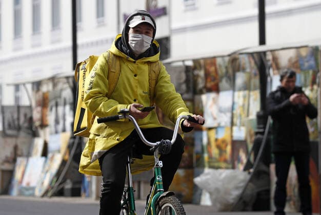 MOSCOW, RUSSIA - MARCH 29, 2020: A food delivery worker in a face mask rides a bicycle in Stary Arbat Street during the pandemic of the novel coronavirus (COVID-19). As of 29 March 2020, Russia has reported more than 1200 confirmed cases of the novel coronavirus (COVID-19), with more than 1000 confirmed cases in Moscow. Artyom Geodakyan TASS  TS0D3C49