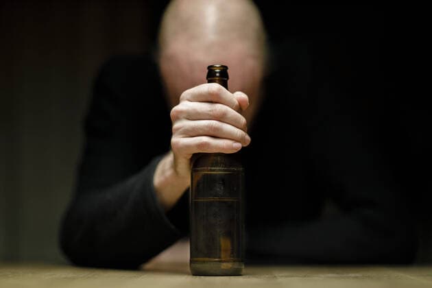 Symbolfoto zum Thema Alkoholismus: Ein Mann sitzt allein zu Hause an einem Tisch und haelt eine Flasche Bier in der Hand. Berlin, 25.03.2020. Berlin Deutschland *** Symbol photo on the subject of alcoholism A man sits alone at home at a table, holding a bottle of beer in his hand Berlin, 25 03 2020 Berlin Germany Copyright: xphotothek xThomasxTrutschelx