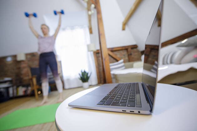 Symbolfoto zum Thema Fitness: Eine Frau trainiert zu Hause mit Hanteln. Neben ihr steht ein Laptop. Berlin, 26.03.2020. Berlin Deutschland