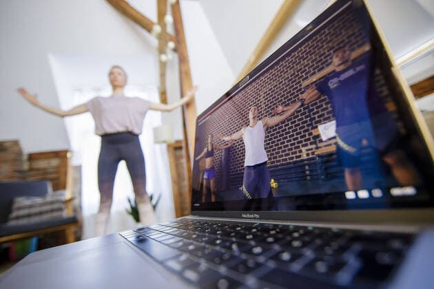 Symbolfoto zum Thema Fitness: Eine Frau trainiert zu Hause mit Hilfe eines Onlinekurses auf Gymondo. Neben ihr steht ein Laptop. Berlin, 26.03.2020. Berlin Deutschland
