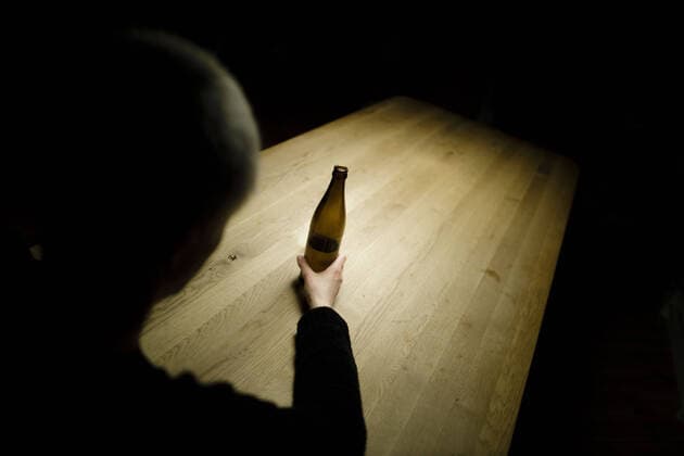 Symbolfoto zum Thema Alkoholismus: Eine Frau sitzt allein zu Hause an einem Tisch und haelt eine Flasche Bier in der Hand. Berlin, 25.03.2020. Berlin Deutschland
