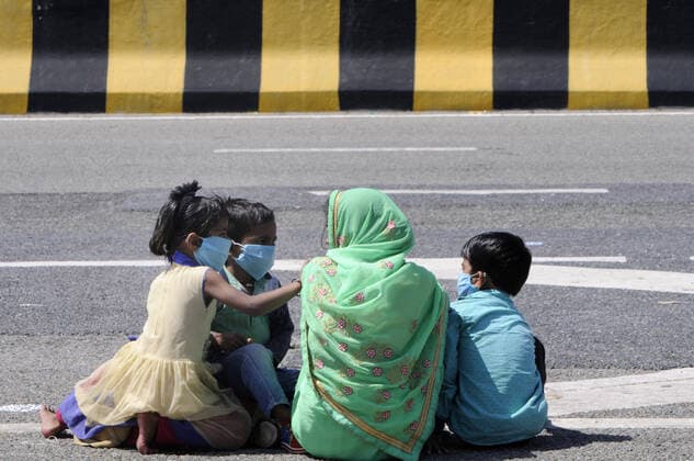 NOIDA, INDIA - MARCH 29: A migrant worker with children headed back home pauses for break, on day 5 of the nationwide lockdown imposed by PM Narendra Modi to check the spread of coronavirus, at Yamuna expressway zero point, on March 29, 2020 in Noida, India. (Photo by Sunil Ghosh Hindustan Times ) Migrant Workers Head Home In Coronavirus Lockdown