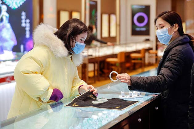 (200330) -- WUHAN, March 30, 2020 -- A customer (L) selects a bracelet at a shopping mall in Wuhan, central China s Hubei Province, March 30, 2020. Many shopping malls in Wuhan reopened on Monday. ) CHINA-WUHAN-SHOPPING MALL-REOPENING (CN) ShenxBohan 