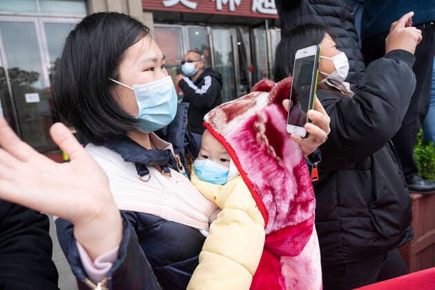 (200330) -- WUHAN, March 30, 2020 -- A woman holding her 15-month-old baby waves goodbye to the medics from Shandong Province in Wuhan, central China s Hubei Province, March 30, 2020. The 3rd and 12th batches of medical workers from Shandong Province left Wuhan on Monday after finishing their task. ) CHINA-WUHAN-COVID-19-MEDICS FROM SHANDONG PROVINCE-DEPARTURE (CN) CaixYang 