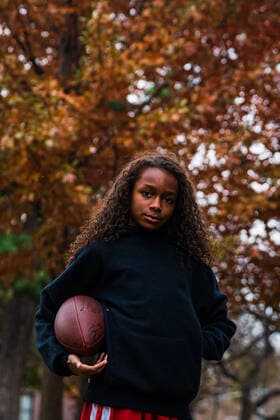 Portrait of confident girl holding American football in park New York, NY, United States ,model released, Symbolfoto CR_LIWEEE200227-318376-01