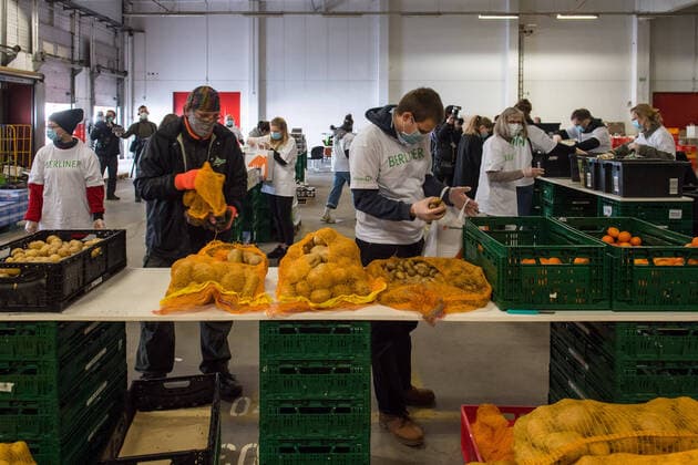 Berlin Corona-Krise Berliner Tafel Auswirkungen der Corona-Krise. Die Corona-Situation hat auch fuer die Hilfsorganisation Berliner Tafel weitreichende Konsequenzen. 42 LAIB und SEELE-Ausgabestellen mussten schliessen, nur drei der Ausgabestellen haben noch geoeffnet. Rund 50.000 beduerftige Menschen kommen ueblicherweise jeden Monat an den Ausgabestellen. Damit die Menschen weiterhin gespendete Lebensmittel erhalten koennen, beliefert die Berliner Tafel nun die Menschen zu Hause. In einer Halle auf dem Berliner Grossmarkt packen freiwillige Helferinnen und Helfer Tueten mit Lebensmitteln (im Bild), die verteilt werden. In einigen Bezirken uebernehmen Radfahrerinnen und Radfahrer der Rebel Riders mit Lastenraedern die Vor-Ort-Verteilung von Tuer zu Tuer. LAIB und SEELE ist eine Aktion der Berliner Tafel e.V., der Kirchen u