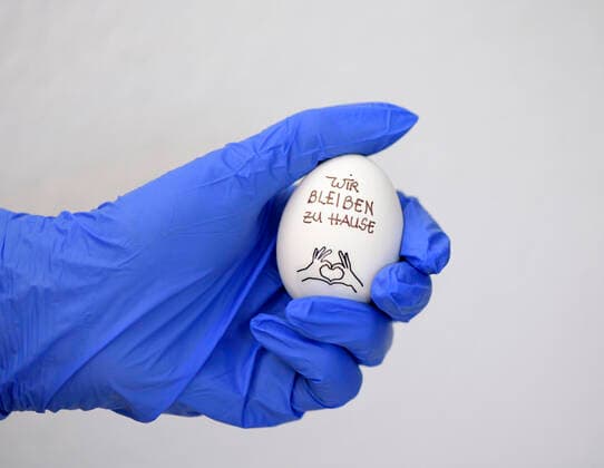 31.03.2020, Symbolbild: Ei und Gummihandschuhe: Wir bleiben zu Hause auf einem Hühnerei. Ein Slogan wegen der Ausgangsbeschränkung in Deutschland. 31.03.2020, Ei und Gummihandschuhe 31.03.2020, Ei und Gummihandschuhe