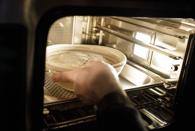 Mann halt ein Gaerkoerbchen mit einem Teig aus Sauerteig ins einen Haenden. Berlin Deutschland