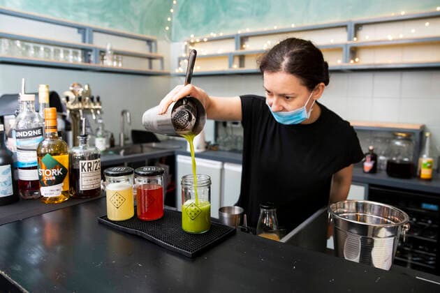 Izabela Rosiak bereitet mit Mundschutzmaske Cocktails in der Bar in der Jar in Berlin Kreuzberg am 31. Maerz 2020. Um die Verbreitung des Coronavirus (SARS-CoV-2) zu verlangsamen beschlossen Bund und Laender weitere Restriktionen. Nachdem Museen, Theatern, Sportveranstaltungen usw verboten wurden sind seit einigen Tagen weitere verschaerfte Massnahmen in Kraft getreten wie z.B. Verbot von Versammlungen in der Oeffentlichkeit mit mehr als zwei Personen, Einhaltung von Mindestabstand zwischen Personen und Schliessung von Gastronomiebetrieben mit Ausnahme von Abholung und Lieferung. Gross wird langsam die Debatte ueber die wirtschaftliche Folgen der Krise und die Laenge und Verhaeltnismaessigkeit der Restritktionen. Unternehmertum waehrend Coronavirus in Berlin