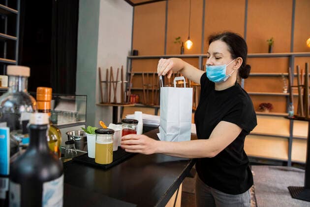 Izabela Rosiak packt Cocktails fuer die Lieferung in einer Tuete in der Bar in der Jar in Berlin Kreuzberg am 31. Maerz 2020. Um die Verbreitung des Coronavirus (SARS-CoV-2) zu verlangsamen beschlossen Bund und Laender weitere Restriktionen. Nachdem Museen, Theatern, Sportveranstaltungen usw verboten wurden sind seit einigen Tagen weitere verschaerfte Massnahmen in Kraft getreten wie z.B. Verbot von Versammlungen in der Oeffentlichkeit mit mehr als zwei Personen, Einhaltung von Mindestabstand zwischen Personen und Schliessung von Gastronomiebetrieben mit Ausnahme von Abholung und Lieferung. Gross wird langsam die Debatte ueber die wirtschaftliche Folgen der Krise und die Laenge und Verhaeltnismaessigkeit der Restritktionen. Unternehmertum waehrend Coronavirus in Berlin