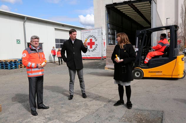 Rüdiger Unger, Stephan Roelen und Petra Köpping beim Empfang einer Großspende von Händedesinfektionsmittelm der Beiersdorf AG an den Freistaat Sachsen bei der DRK Logistik HUB Sachsen GmbH. Dresden, 31.03.2020