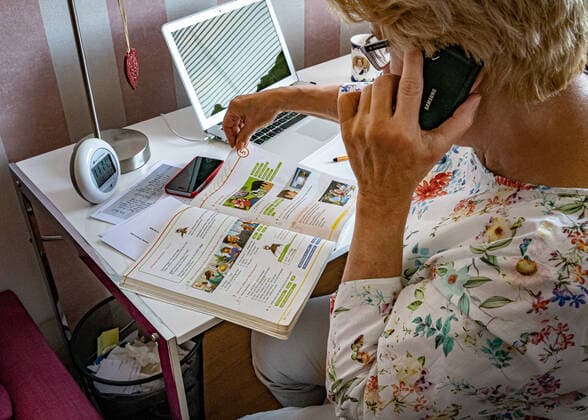 Bildung: Lehrerin, Hausaufgaben korrigieren, Korrektur, Schule, Zensur, Zensuren, -während die Schule wegen Coronavirus Covid-19 geschlossen ist, unterrichtet Lehrerin per Telefon und MacBook die Schüler aus dem Homeoffice *Model release* Lehrerin