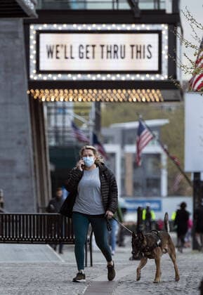A woman walks her dog under a sign of encouragement after the DC Government issues a stay at home order to help combat the Coronavirus, COVID-19, pandemic, in Washington, D.C. on Wednesday, April 1, 2020.  WAP20200401303 KEVINxDIETSCH