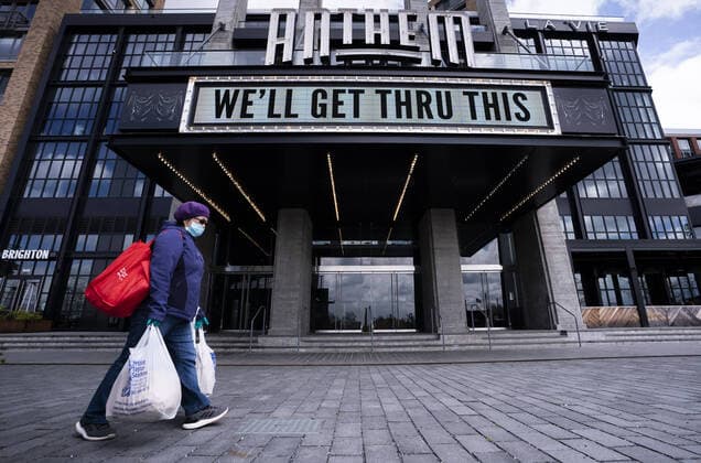 A woman wears a mask as she walks under the Anthem s marquee sign after the DC Government issues a stay at home order to help combat the Coronavirus, COVID-19, pandemic, in Washington, D.C. on Wednesday, April 1, 2020.  WAP20200401304 KEVINxDIETSCH