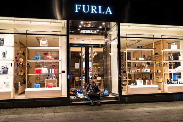 Ein Obdachloser, der seine provisorische Unterkunft am eingang einer Boutique fuer Luxustaschen Furla gemacht hat, liest die Zeitung am Kudamm in Berlin am 1. April 2020. Um die Verbreitung des Coronavirus (SARS-CoV-2) zu verlangsamen beschlossen Bund und Laender weitere Restriktionen. Nachdem Museen, Theatern, Sportveranstaltungen usw verboten wurden sind seit einigen Tagen weitere verschaerfte Massnahmen in Kraft getreten wie z.B. Verbot von Versammlungen in der Oeffentlichkeit mit mehr als zwei Personen, Einhaltung von Mindestabstand zwischen Personen und Schliessung von Gastronomiebetrieben mit Ausnahme von Abholung und Lieferung. Coronavirus in Berlin