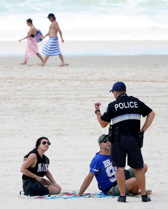 AUSTRALIA CORONAVIRUS COVID-19, A policeman speaks with sunbathers on Surfers Paradise Beach on the Gold Coast, Thursday, April 2, 2020. Exercise is one of only eight essential reasons residents in Queensland are allowed to leave their home, as part of the Queensland Governments battle against COVID-19. ( NO ARCHIVING, EDITORIAL USE ONLY, NO USE IN BOOKS WITHOUT CONSENT GOLD COAST QLD AUSTRALIA  Copyright: xDAVExHUNTx 20200402001461367750