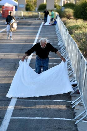 April 1, 2020 - Las Vegas, Nevada, U.S. - A man prepares a place to sleep in an area marked by painted boxes at a temporary homeless shelter set up in a parking lot at Cashman Center amid the coronavirus pandemic on April 1, 2020, in Las Vegas, Nevada. Local officials opened the makeshift shelter after another local shelter closed when a homeless man staying there tested positive for the coronavirus. Las Vegas USA - ZUMAbk3_ 20200401_zaf_bk3_004 Copyright: xDavidxBeckerx