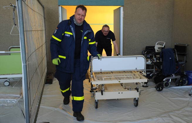 20 Helfer vom THW, DRK, DRLG und der Feuerwehr helfen am Donnerstag (02.04.2020) beim Aufbau der Betten in der Turnhalle in Marpingen. Die Sporthalle soll als Versorgungszentrum für Coronapatienten dienen. Insgesamt 42 Betten werden von den Helfern in Krankenhäusern und Pflegeheimen abgeholt und in die Turnhalle gebracht und aufgestellt.