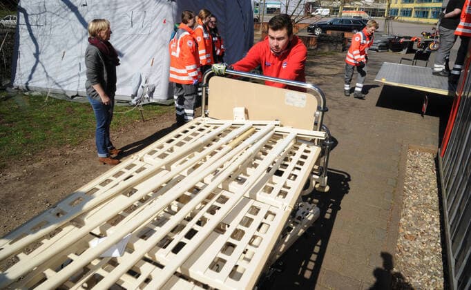 20 Helfer vom THW, DRK, DRLG und der Feuerwehr helfen am Donnerstag (02.04.2020) beim Aufbau der Betten in der Turnhalle in Marpingen. Die Sporthalle soll als Versorgungszentrum für Coronapatienten dienen. Insgesamt 42 Betten werden von den Helfern in Krankenhäusern und Pflegeheimen abgeholt und in die Turnhalle gebracht und aufgestellt.