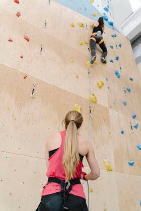 Woman with a rope securing partner on the wall in climbing gym model released Symbolfoto property released  AHSF01961
