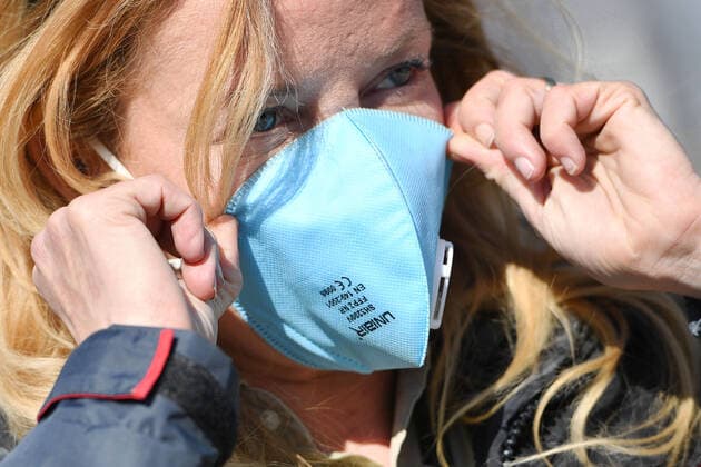 Eine Frau zieht sich eine FFP2 Mundschutzmaske in Gesicht. Maske,Schutzmaske,Mundschutz.Virenschutz, Zu viele Corona-Infektionen: Muenchner Helios Klinik gibt Alltagsbetrieb auf. Wegen einer Vielzahl von Corona-Infektionen unter Patienten und Mitarbeitern gibt die Muenchner Klinik den normalen Krankenhausbetrieb voruebergehend auf. Auch die Notaufnahme ist betroffen. So sollen Infektionsketten unterbrochen werden, am 02.04.2020