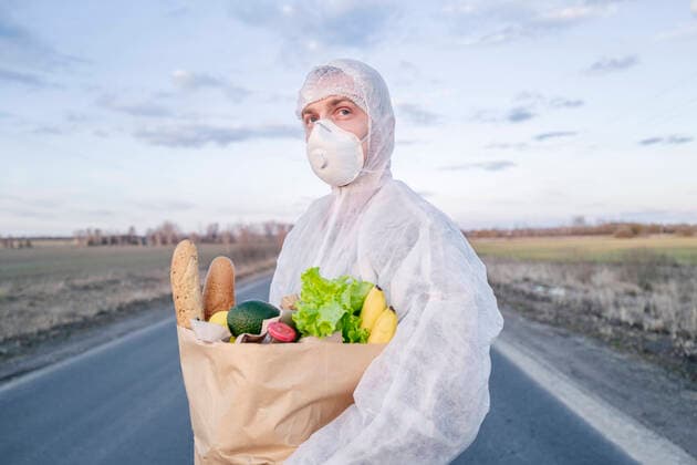 Man wearing protective suit and mask holding grocery bag on a country road model released Symbolfoto  EYAF00969