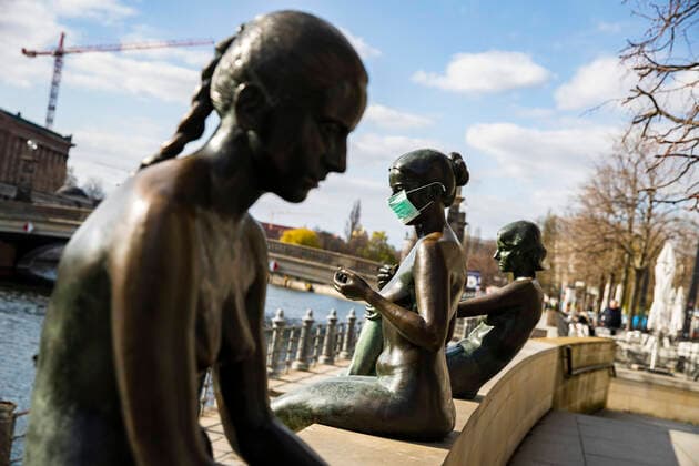 Gestelltes Bild: Statue mit Mundschutzmaske am Spreeufer in Berlin am 2. April 2020. Um die Verbreitung des Coronavirus (SARS-CoV-2) zu verlangsamen beschlossen Bund und Laender weitere Restriktionen. Nachdem Museen, Theatern, Sportveranstaltungen usw verboten wurden sind seit einigen Tagen weitere verschaerfte Massnahmen in Kraft getreten wie z.B. Verbot von Versammlungen in der Oeffentlichkeit mit mehr als zwei Personen, Einhaltung von Mindestabstand zwischen Personen und Schliessung von Gastronomiebetrieben mit Ausnahme von Abholung und Lieferung. Coronavirus in Berlin