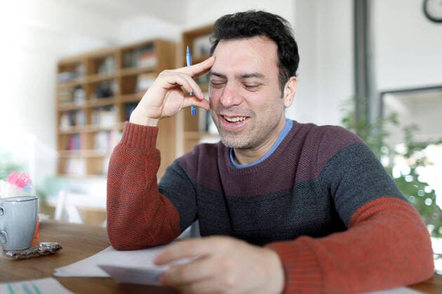 Portrait of mature man sitting at table at home looking at documents model released Symbolfoto property released  KMKF01226