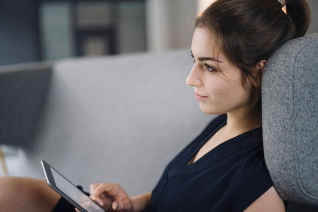 IMAGO Creative: Jahreszeit Winter, Couching Young businesswoman sitting on couch with digital tablet looking at distance model released Symbolfoto property released  KNSF07627