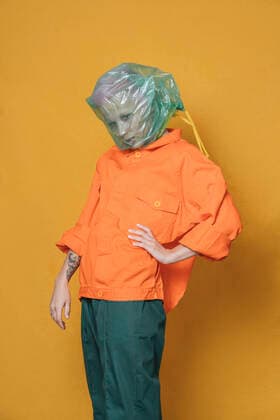 Portrait of young woman wearing orange jacket in front of yellow background model released Symbolfoto  VPIF02114