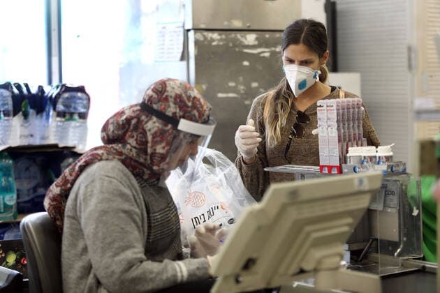 (200403) -- TEL AVIV, April 3, 2020 (Xinhua) -- A customer and a cashier wearing protective gears are seen at a shop in the central Israeli city of Tel Aviv on April 2, 2020. Israel reported 765 new confirmed cases of COVID-19 on Thursday, the daily highest so far, bringing the total number to 6,857, said the Ministry of Health. (Gideon Markowicz JINI Handout via Xinhua) MIDEAST-TEL AVIV-COVID-19 