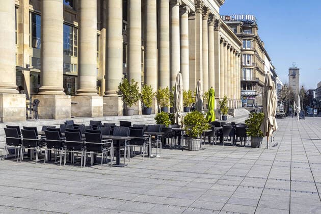 DEU, Deutschland, Baden-Württemberg, Stuttgart, 03.04.2020: Königsbau an der Fußgängerzone Stuttgart Königstraße. Aufgrund einer Allgemeinverfügung bleiben die Läden geschlossen, Fußgänger sind nur vereinzelt unterwegs. Leeres Straßencafe am Schlossplatz.
