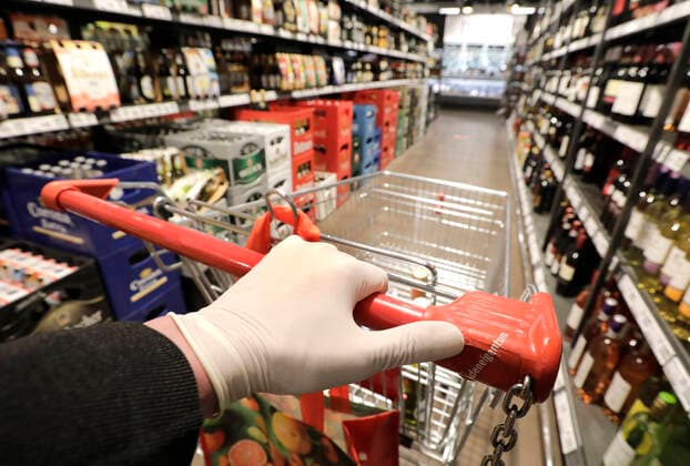 Eine Hand mit einem Einmalhandschuh am Griff eines Einkaufswagens in einem Supermarkt, DEU, Berlin, 03.04.2020