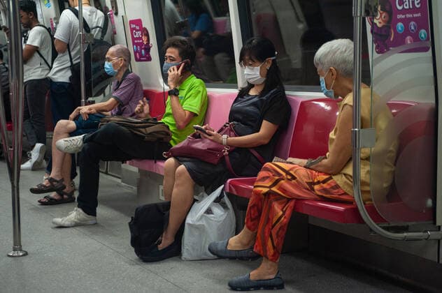 02.04.2020, Singapur, Republik Singapur, Asien - Fahrgaeste tragen in einer U-Bahn Atemschutzmasken, um sich vor einer Ansteckung mit dem pandemischen Coronavirus zu schuetzen. Die meisten Leute befolgen das Prinzip der Safe Distancing Massnahmen, in dem ein leerer Sitz zwischen ihnen und dem Sitznachbarn freigelassen wird.