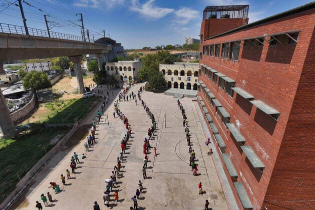 NEW DELHI, INDIA - APRIL 3: An aerial view of people queuing to collect food distributed by Delhi Government on day ten of the 21-day nationwide lockdown to curb the spread of coronavirus, at Government Senior Secondary School, Harkesh Nagar on April 3, 2020 in New Delhi, India. (Photo by Burhaan Kinu Hindustan Times) Government And NGOs Provide Food To Homeless And Poor Amid Lockdown To Prevent Covid-19
