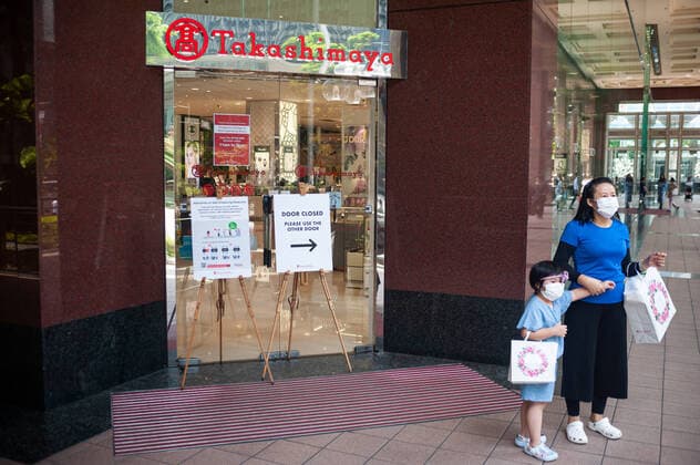 02.04.2020, Singapur, Republik Singapur, Asien - Eine Mutter steht mit ihrem Kind vor dem Takashimaya Einkaufszentrum an der Orchard Road. Beide tragen einen Mundschutz, um eine Ansteckung mit dem pandemischen Coronavirus zu verhindern.