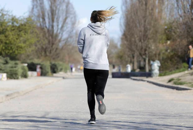 Eine junge Frau joggt am Samstagmorgen im Mauerpark waehrend der Corona-Krise, DEU, Berlin, 04.04.2020