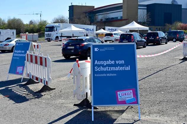 04.04.20, Oberhausen, Nordrhein-Westfalen, Deutschland. Corona Krise. Auf dem Gelaende eines Parkplatzes am Centro Oberhausen wird Schutzmaterial fuer Aerzte von der Kassenaerztlichen Vereinigung Niederrhein kostenlos verteilt. Mittels eines zugestellten QR-Codes koennen die Aerzte ihre Kartons an der Ausgabestelle abholen. Zwei LKW-Ladungen mit Kartons stehen bereit. In jedem KArton befinden sich Desinfektionsmittel und Mundschutzmasken, die aus China impotiert wurden. Blick auf die Zufahrt zur Ausgabestelle. Alltagsleben waehrend der Corona Krise