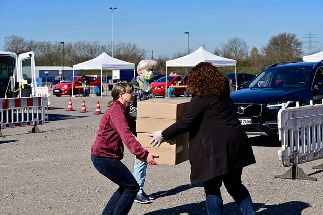 04.04.20, Oberhausen, Nordrhein-Westfalen, Deutschland. Corona Krise. Auf dem Gelaende eines Parkplatzes am Centro Oberhausen wird Schutzmaterial fuer Aerzte von der Kassenaerztlichen Vereinigung Niederrhein kostenlos verteilt. Mittels eines zugestellten QR-Codes koennen die Aerzte ihre Kartons an der Ausgabestelle abholen. Zwei LKW-Ladungen mit Kartons stehen bereit. In jedem KArton befinden sich Desinfektionsmittel und Mundschutzmasken, die aus China impotiert wurden. Ehrenamtliche Helfer bringen die Kartons zu den Abholberechtigten Aerzten. Alltagsleben waehrend der Corona Krise