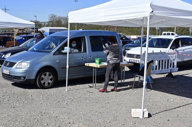 04.04.20, Oberhausen, Nordrhein-Westfalen, Deutschland. Corona Krise. Auf dem Gelaende eines Parkplatzes am Centro Oberhausen wird Schutzmaterial fuer Aerzte von der Kassenaerztlichen Vereinigung Niederrhein kostenlos verteilt. Mittels eines zugestellten QR-Codes koennen die Aerzte ihre Kartons an der Ausgabestelle abholen. Zwei LKW-Ladungen mit Kartons stehen bereit. In jedem KArton befinden sich Desinfektionsmittel und Mundschutzmasken, die aus China impotiert wurden. Ehrenamtliche Helferin ueberprueft an der Einfahrt zur Ausgabestelle die jeweiligen QR-Codes auf dem Anschreiben, die den Aerzten zugestellt wurden. Alltagsleben waehrend der Corona Krise