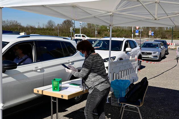 04.04.20, Oberhausen, Nordrhein-Westfalen, Deutschland. Corona Krise. Auf dem Gelaende eines Parkplatzes am Centro Oberhausen wird Schutzmaterial fuer Aerzte von der Kassenaerztlichen Vereinigung Niederrhein kostenlos verteilt. Mittels eines zugestellten QR-Codes koennen die Aerzte ihre Kartons an der Ausgabestelle abholen. Zwei LKW-Ladungen mit Kartons stehen bereit. In jedem KArton befinden sich Desinfektionsmittel und Mundschutzmasken, die aus China impotiert wurden. Ehrenamtliche Helferin ueberprueft an der Einfahrt zur Ausgabestelle die jeweiligen QR-Codes auf dem Anschreiben, die den Aerzten zugestellt wurden. Alltagsleben waehrend der Corona Krise