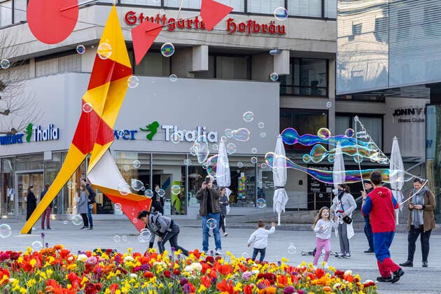 DEU, Deutschland, Baden-Württemberg, Stuttgart, 04.04.2020: Kontaktsperre zeigt Wirkung: Trotz schönen Frühlingwetters halten sich die meisten Menschen an die Kontaktsperre und sind allein oder zu zweit unterwegs. Vor dem Kunstmuseum am Schlossplatz erzeugt ein Straßenkünstler Seifenblasen.