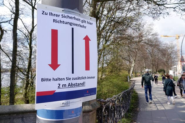 Kontaktverbot - Außenalster 04.04.2020, DEU, Deutschland, Hamburg: Menschen sind an der Alster während des Kontaktverbots wegen der Coronakrise unterwegs. An einem Baum hängt ein Schild mit 2 Pfeilen, darauf ist die Aufschrift **Zu ihrer Sicherheit herrscht hier Richtungsverkehr - Bitte halten sie zusätzlich immer 2 Meter Abstand**. Hamburg Hamburg Deutschland