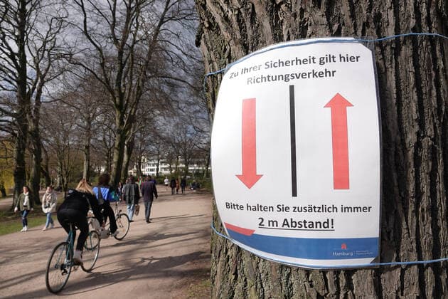 Kontaktverbot - Außenalster 04.04.2020, DEU, Deutschland, Hamburg: Menschen sind an der Alster während des Kontaktverbots wegen der Coronakrise unterwegs. An einem Baum hängt ein Schild mit 2 Pfeilen, darauf ist die Aufschrift **Zu ihrer Sicherheit herrscht hier Richtungsverkehr - Bitte halten sie zusätzlich immer 2 Meter Abstand**. Hamburg Hamburg Deutschland