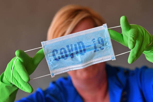 News Bilder des Tages FOTOMONTAGE: Themenbild Coronavirus Pandemie: Schutzmaske und Schutzhandschuhe. Eine Person haelt mit gruenen Schutzhandschuhen einen einfachen Gesichtsschutz,Maske,einfache Schutzmaske,