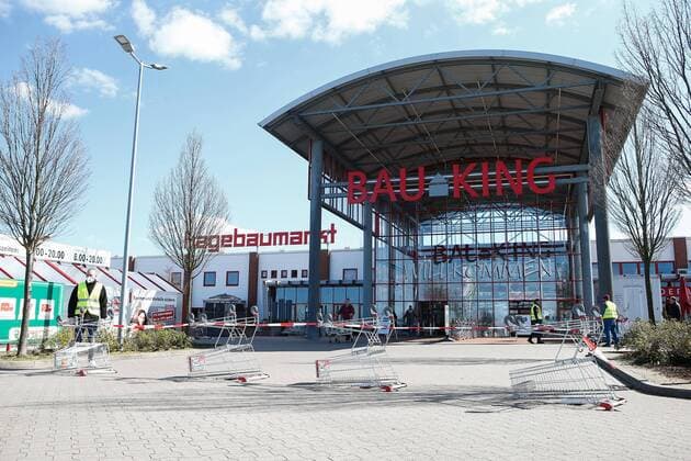 04.04.2020, xtgx, Auswirkungen des Corona Virus in Wolfsburg, Mitarbeiter des Sicherheitsdienstes kontrollieren den Eingang des Bau King (Hagebaumarkt, Hagebau, Baumarkt) in Vorsfelde (Wolfsburg). In Niedersachsen duerfen seit diesem Samstag die Baumaerkte wieder fuer Privatpersonen oeffnen, allerdings darf nur eine bestimmte Zahl von Kunden mit Einkaufswagen in den Markt. Wolfsburg